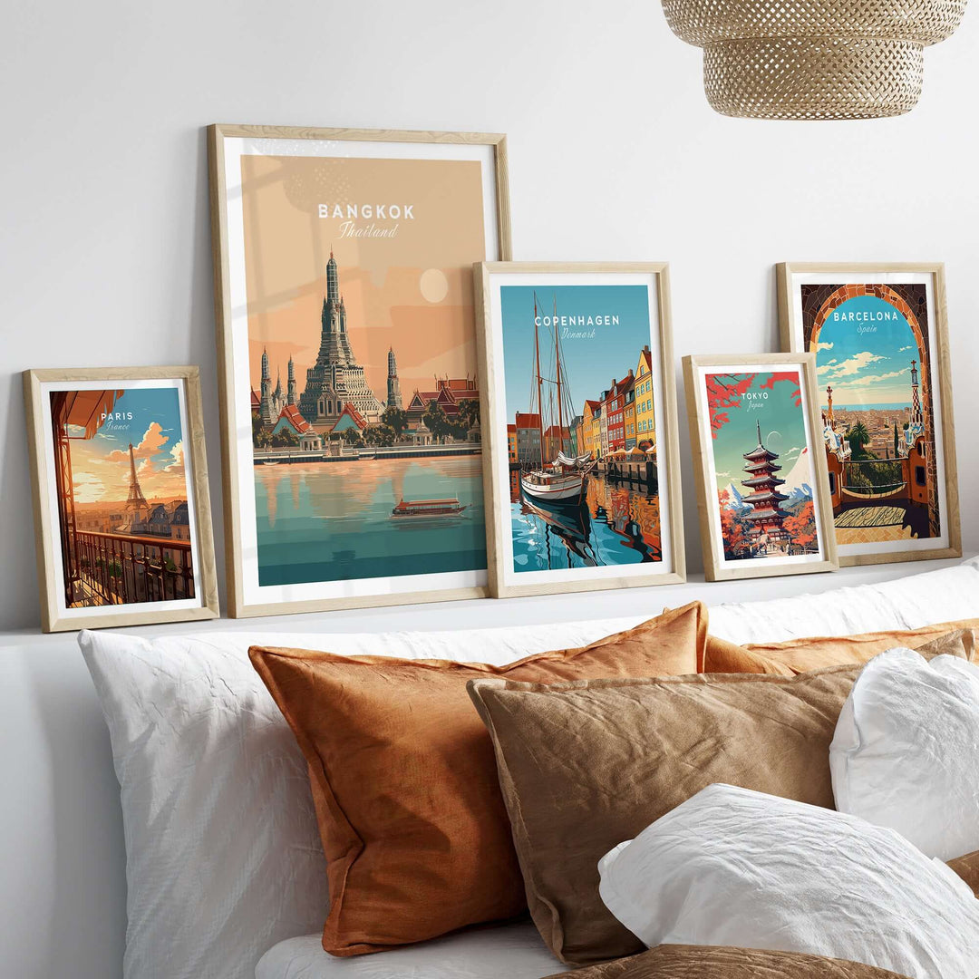 Framed prints of iconic landmarks including Bangkok's Wat Arun on a cozy bed with decorative pillows.
