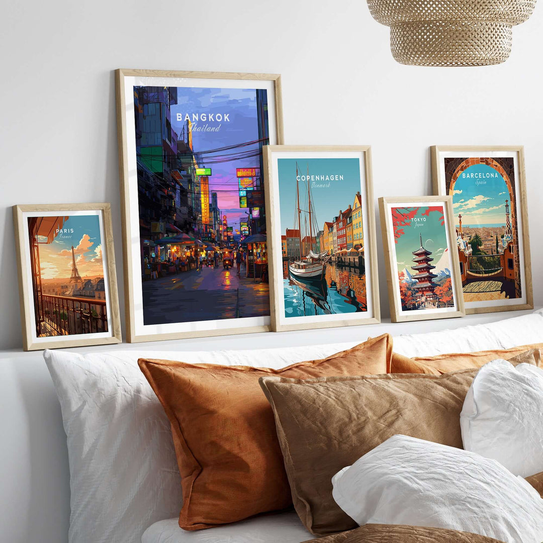 Framed travel posters of Bangkok, Copenhagen, and Barcelona displayed on a stylish sofa, showcasing vibrant cityscapes.