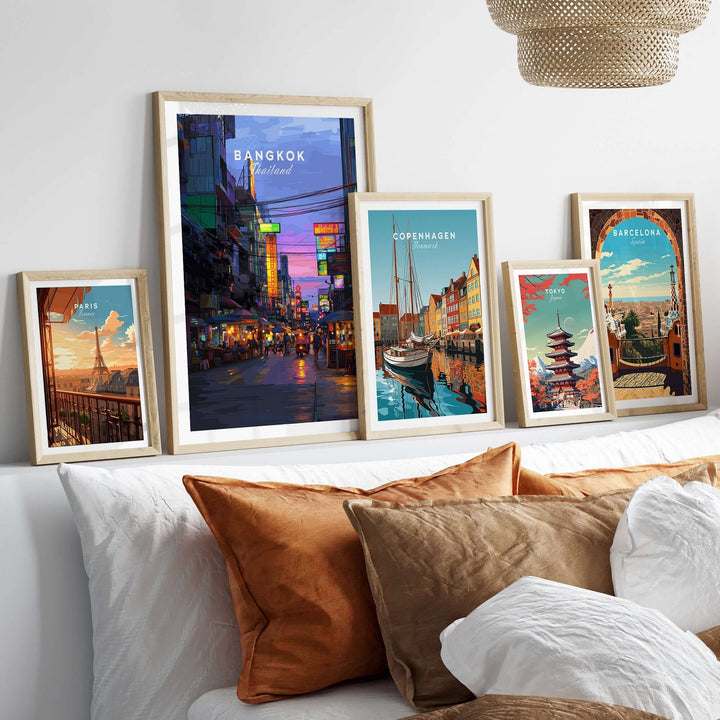 Framed travel posters of Bangkok, Copenhagen, and Barcelona displayed on a stylish sofa, showcasing vibrant cityscapes.