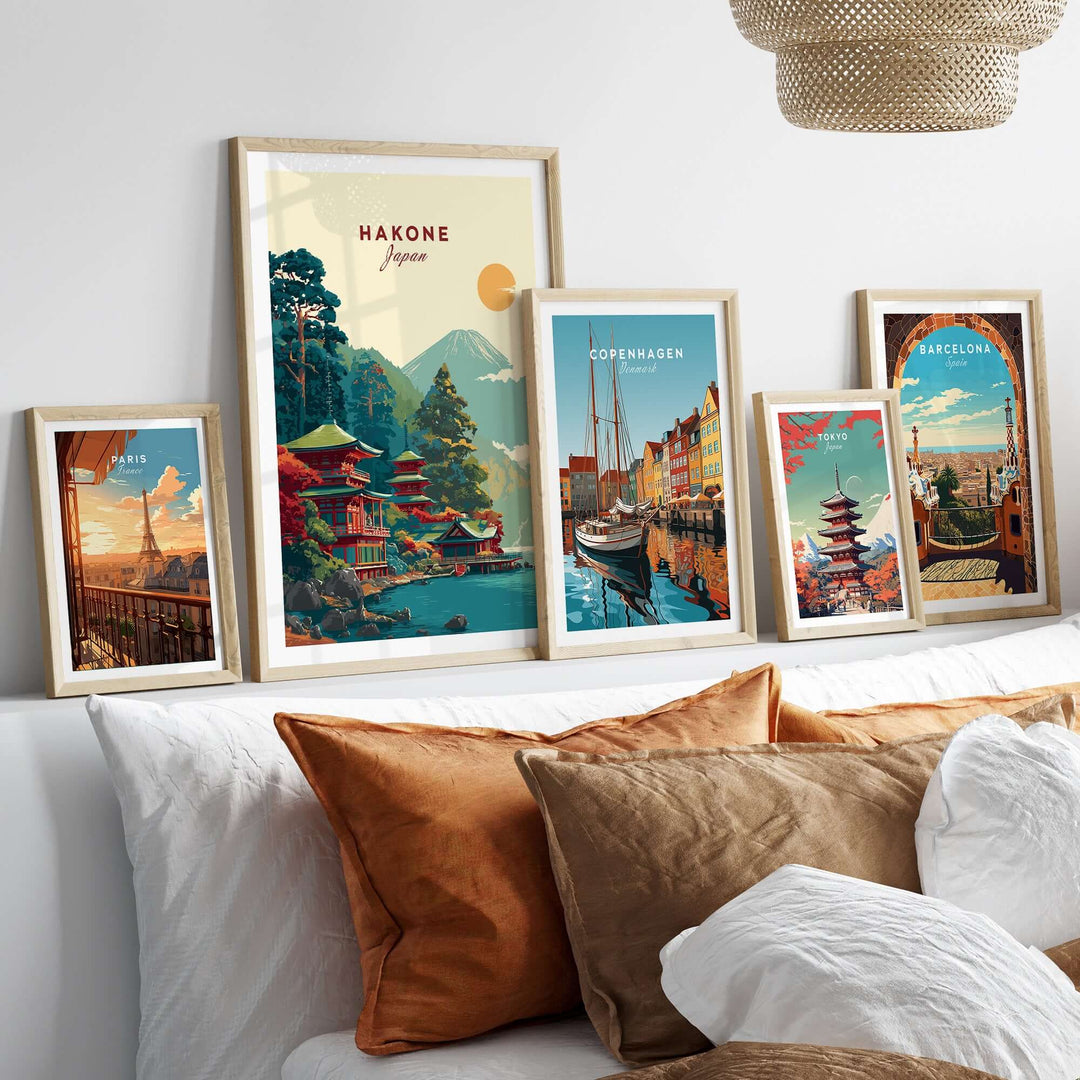 Framed prints of Hakone Japan, Copenhagen, and Barcelona artworks displayed on a cozy bed.