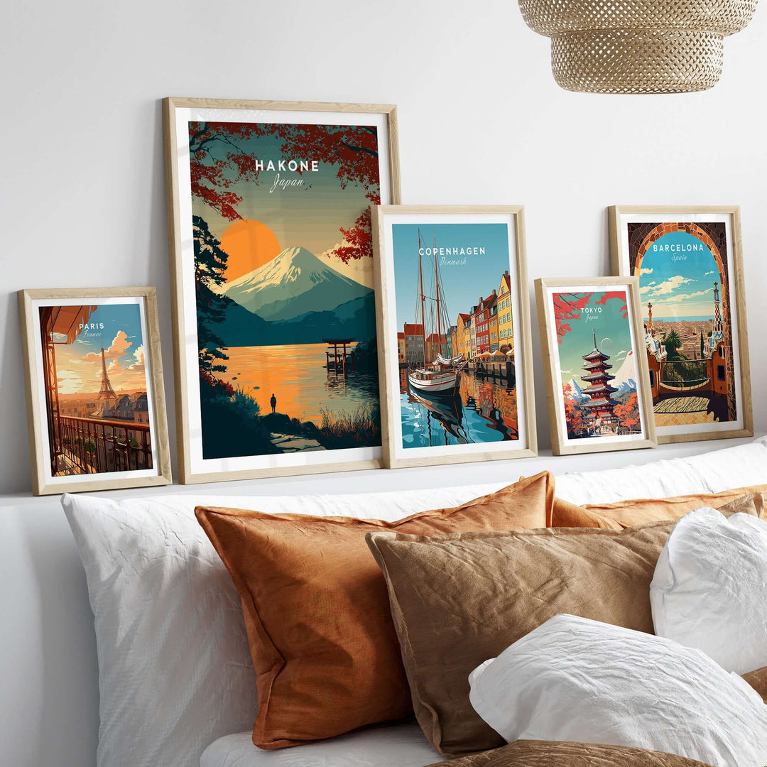 Framed posters of Hakone, Copenhagen, and Barcelona artwork on a stylish couch with warm decor.