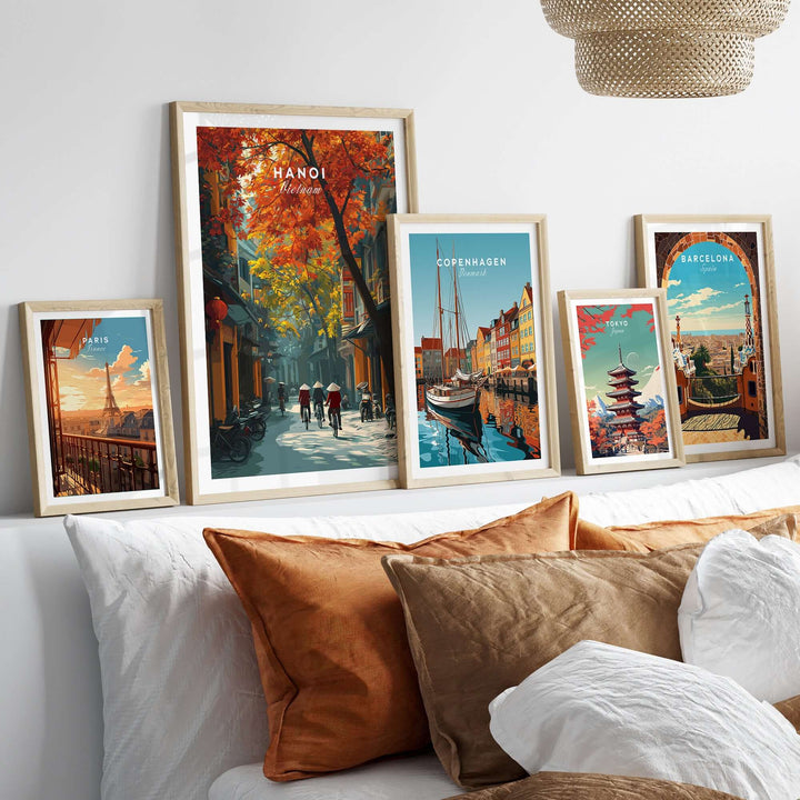 Hanoi poster with vibrant city street print among framed artworks on a cozy wall above a sofa.