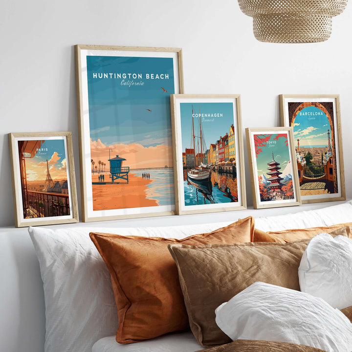 Huntington Beach Lifeguard Tower print with coastal art prints displayed above a bed with warm pillows.