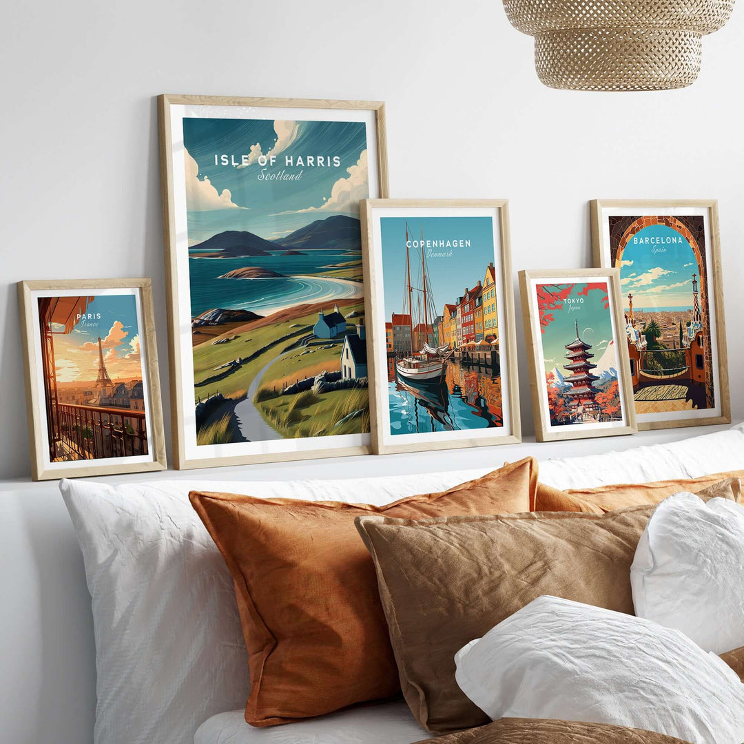 Framed Isle of Harris beach print and other city art on a cozy bed with decorative pillows.