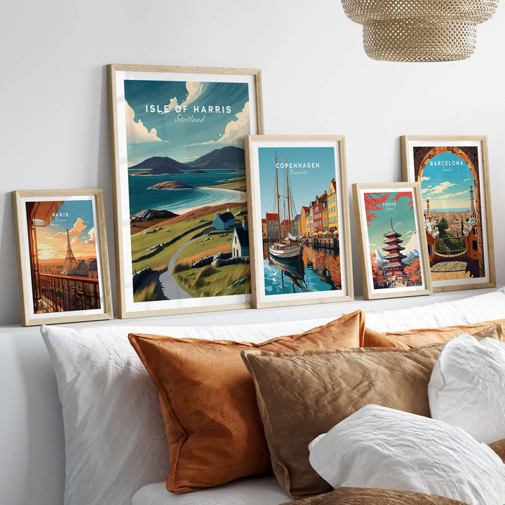 Framed Isle of Harris beach print and other city art on a cozy bed with decorative pillows.