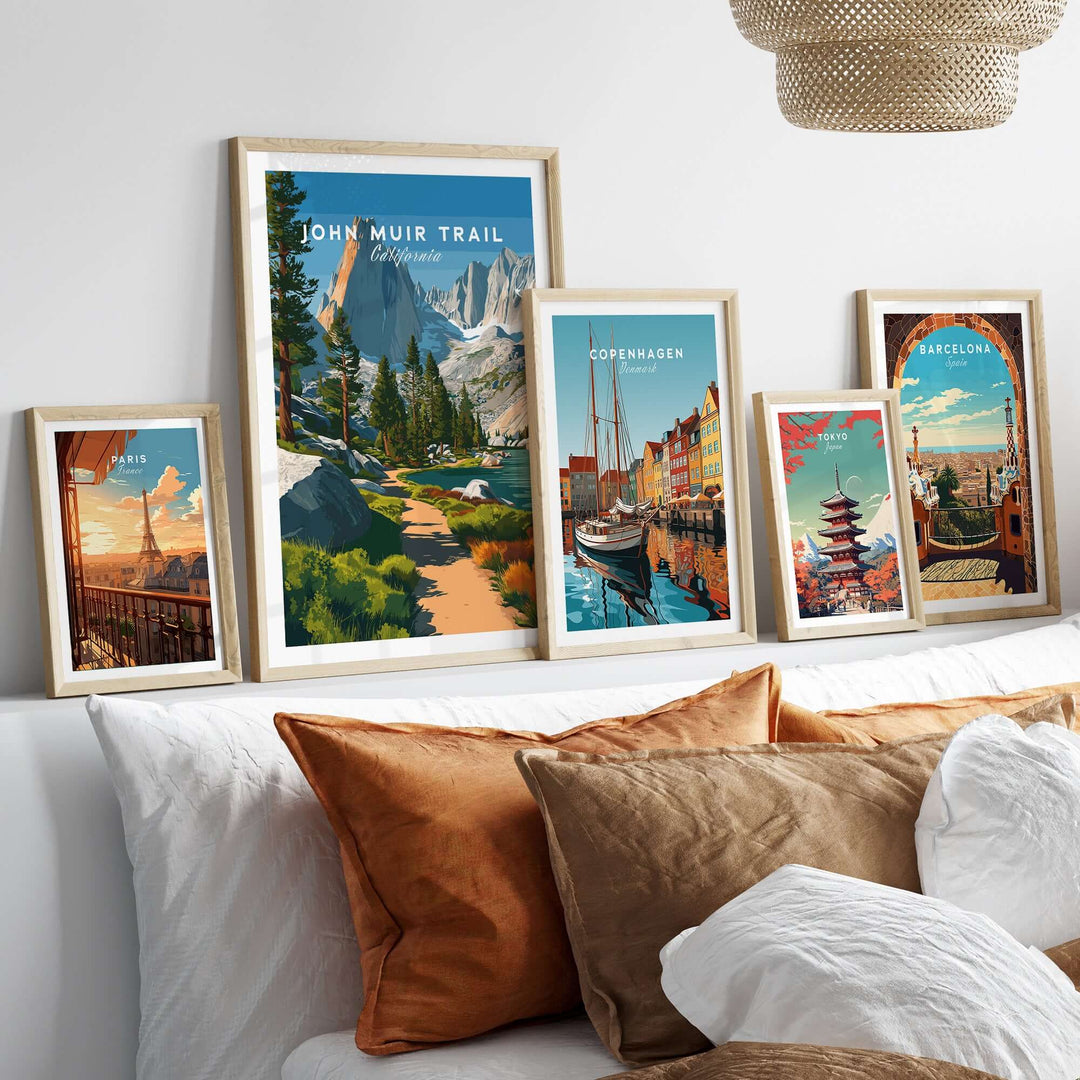 John Muir Trail poster and travel prints displayed on a cozy couch, showcasing scenic landscapes and vibrant city views.