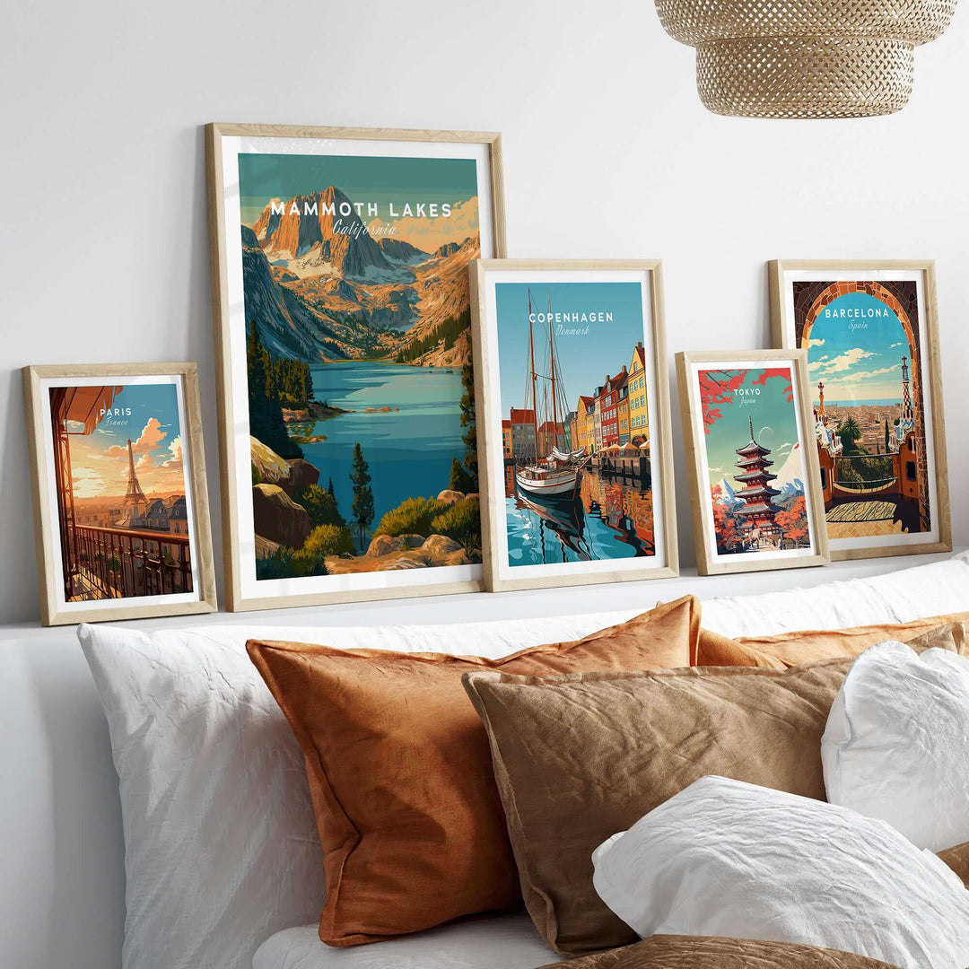 Mammoth Lakes poster and other travel artwork framed on a cozy sofa with pillows, showcasing scenic landscapes and city views