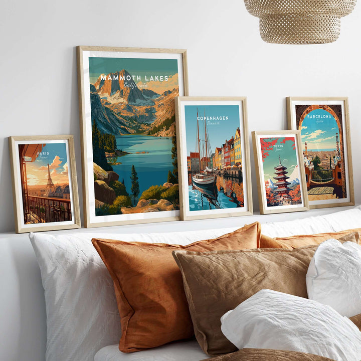Mammoth Lakes poster and other travel artwork framed on a cozy sofa with pillows, showcasing scenic landscapes and city views