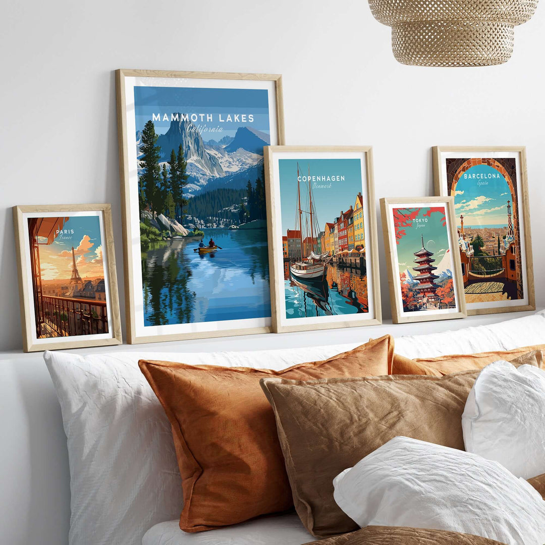 Framed Mammoth Lakes mountain adventure wall art with other city-themed prints on a cozy bed.