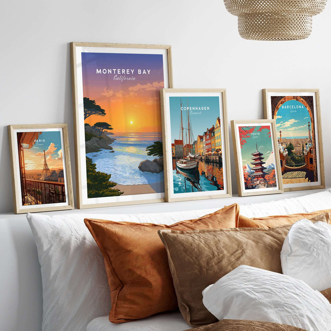 Monterey Bay California sunset print displayed among travel artwork on a stylish bed with decorative pillows.