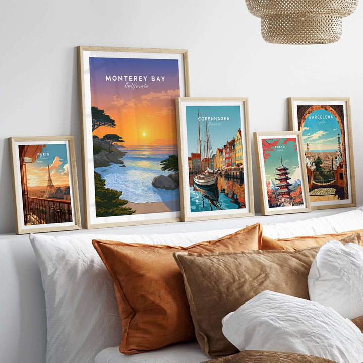 Monterey Bay California sunset print displayed among travel artwork on a stylish bed with decorative pillows.