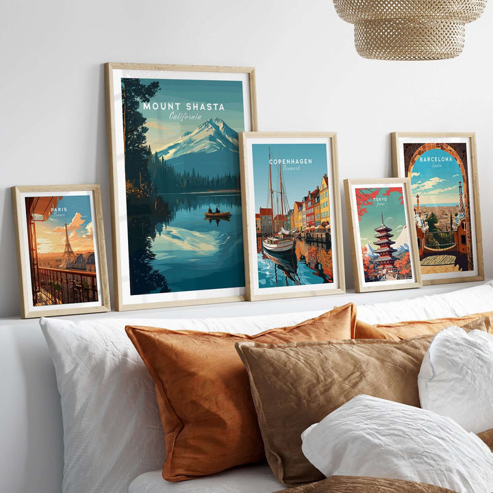 Framed prints showcasing Mount Shasta and other cities, displayed on a wall above a cozy couch with warm pillows.