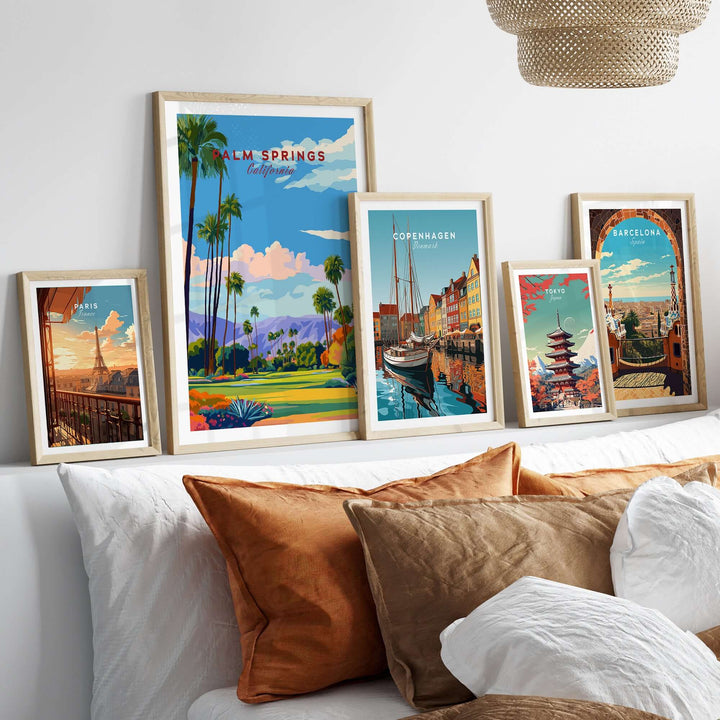 Collection of vibrant travel posters including Palm Springs, Copenhagen, and Barcelona displayed above a stylized bed.