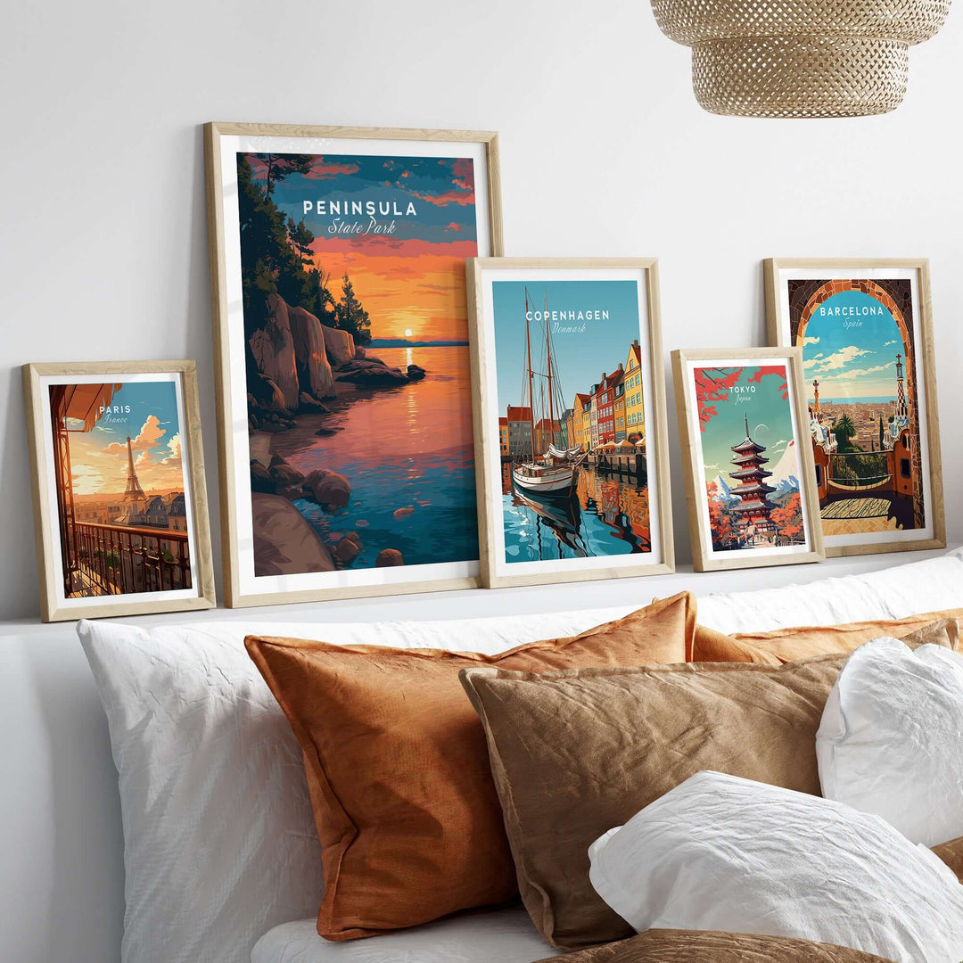 Framed Peninsula State Park sunset print with other city wall art on a modern bed with decorative pillows.