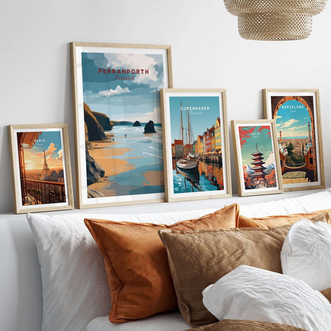 Collection of framed travel posters including Perranporth, displayed above stylish cushions on a cozy sofa.