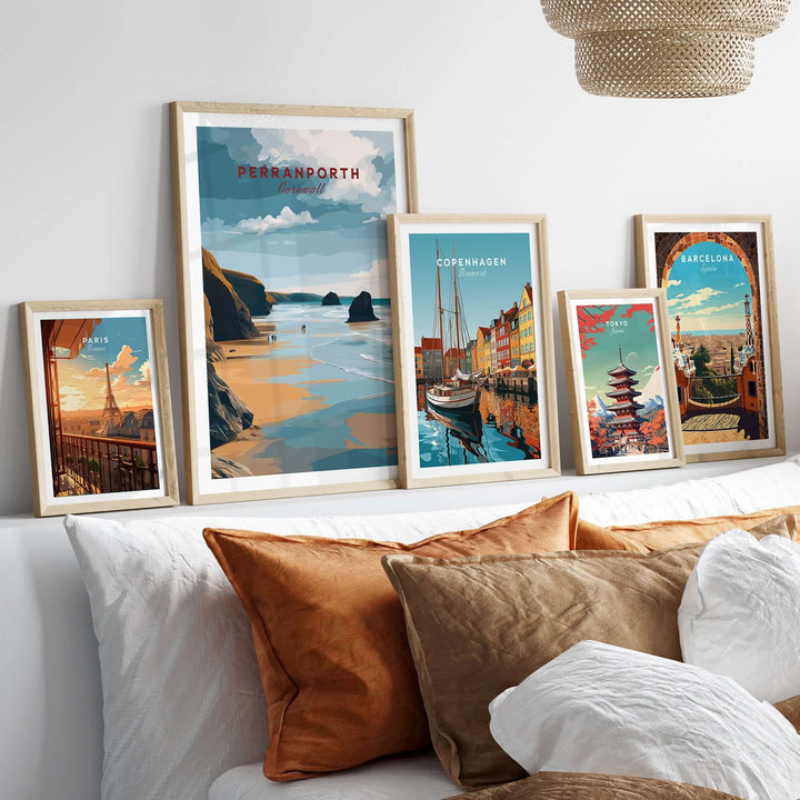 Collection of framed travel posters including Perranporth, displayed above stylish cushions on a cozy sofa.