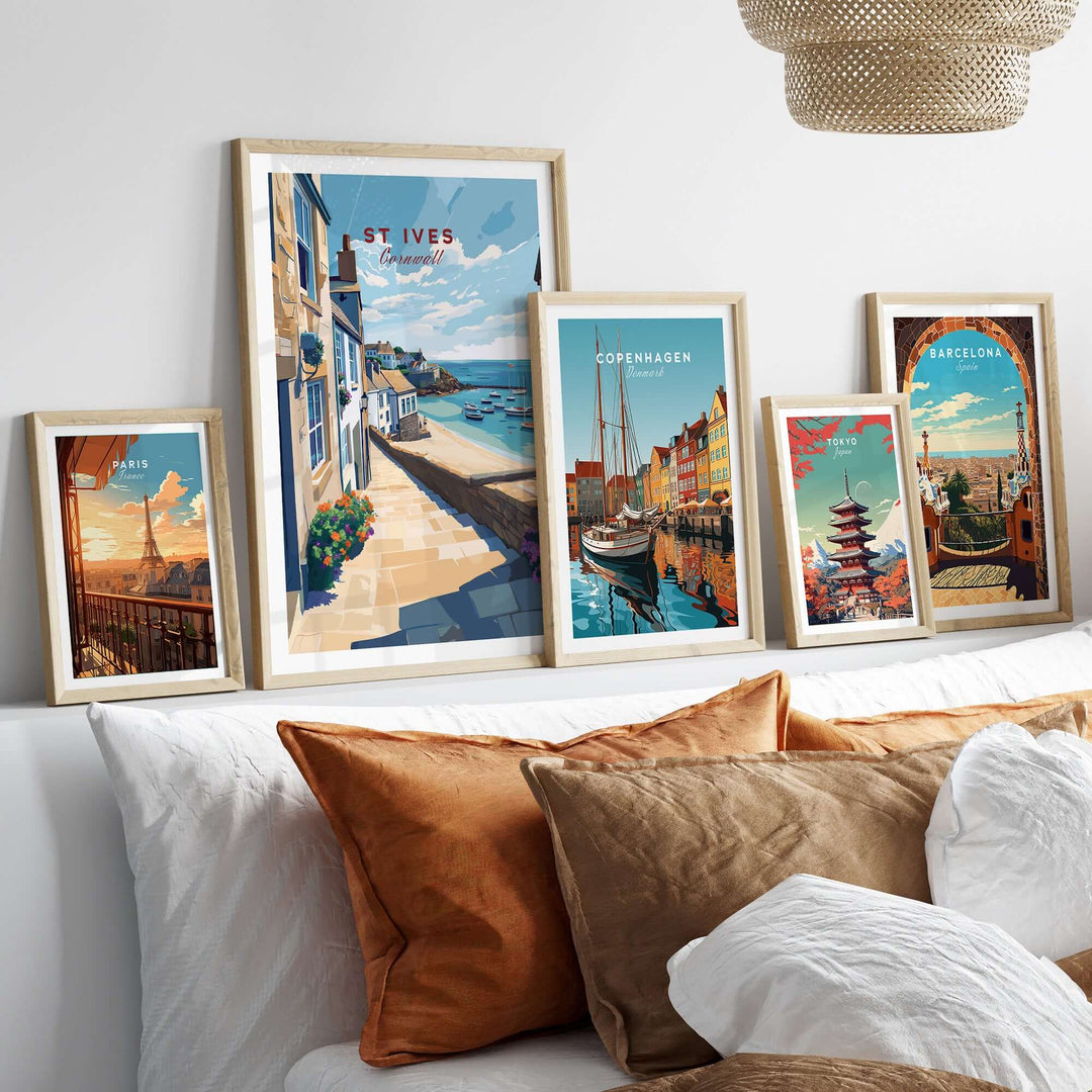 Stylish display of travel posters including St Ives, Copenhagen, and Barcelona over a cozy bed with decorative pillows.