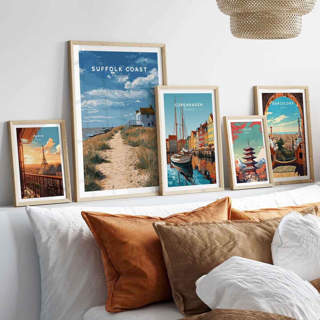 Suffolk Coast beach house print and coastal pathway artwork displayed on a wall above a cozy bed with decorative pillows.