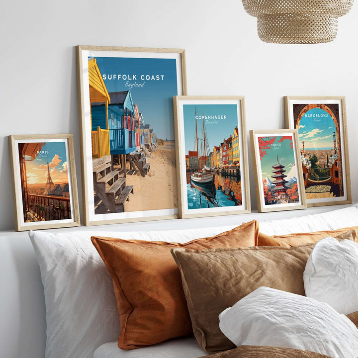 Framed prints of Suffolk Coast beach huts and other cityscapes displayed over a cozy sofa.