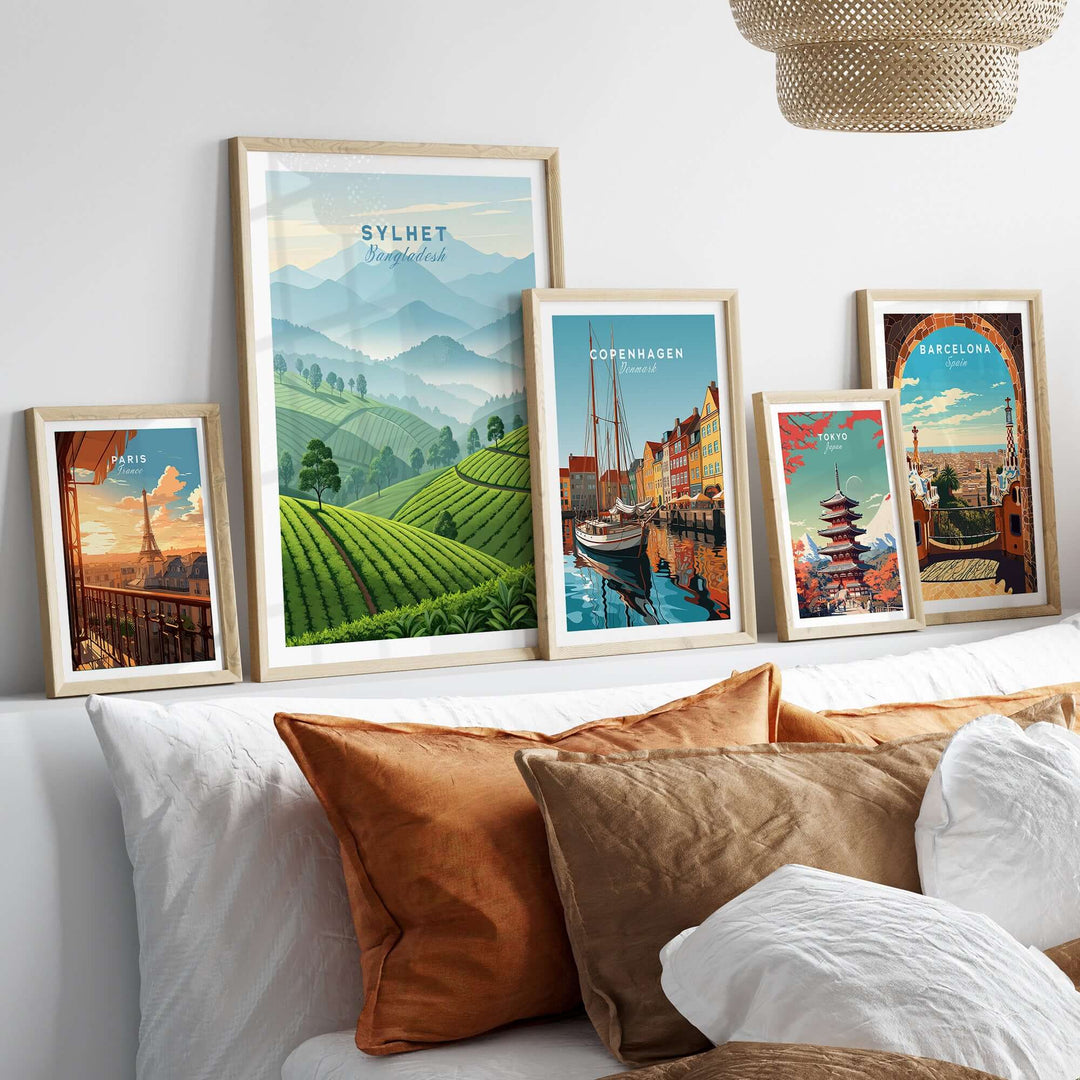 Sylhet wall art featuring tea estates and mountains, displayed among other city posters on a cozy sofa.