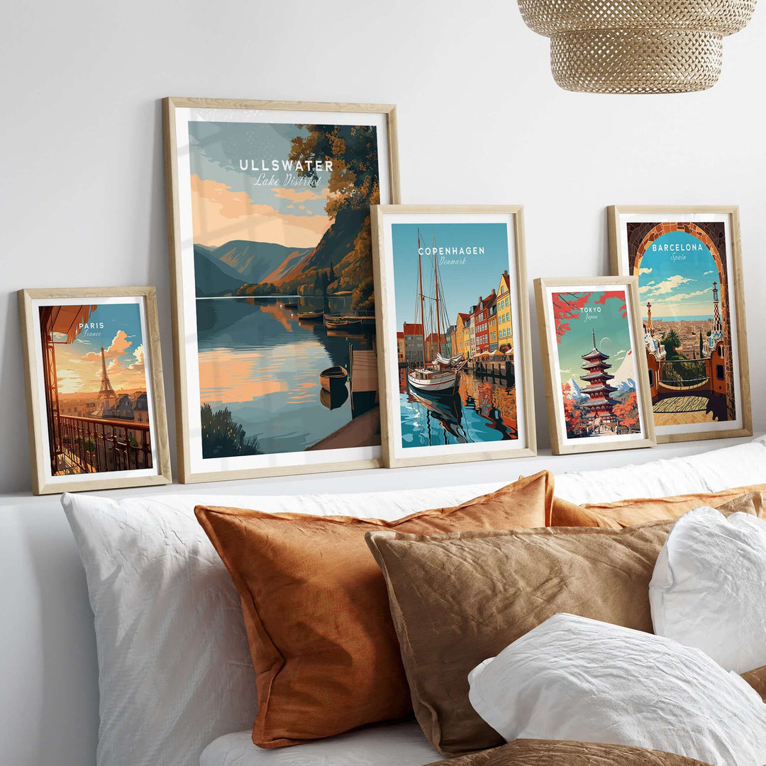 Framed Ullswater Lake District poster among other travel-themed prints on a cozy sofa with decorative cushions.