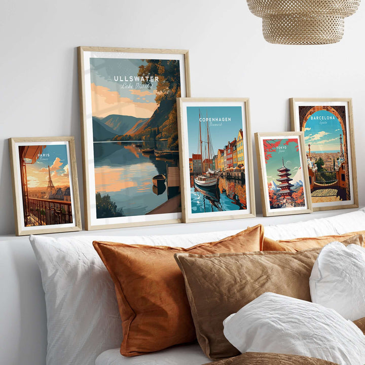 Framed Ullswater Lake District poster among other travel-themed prints on a cozy sofa with decorative cushions.