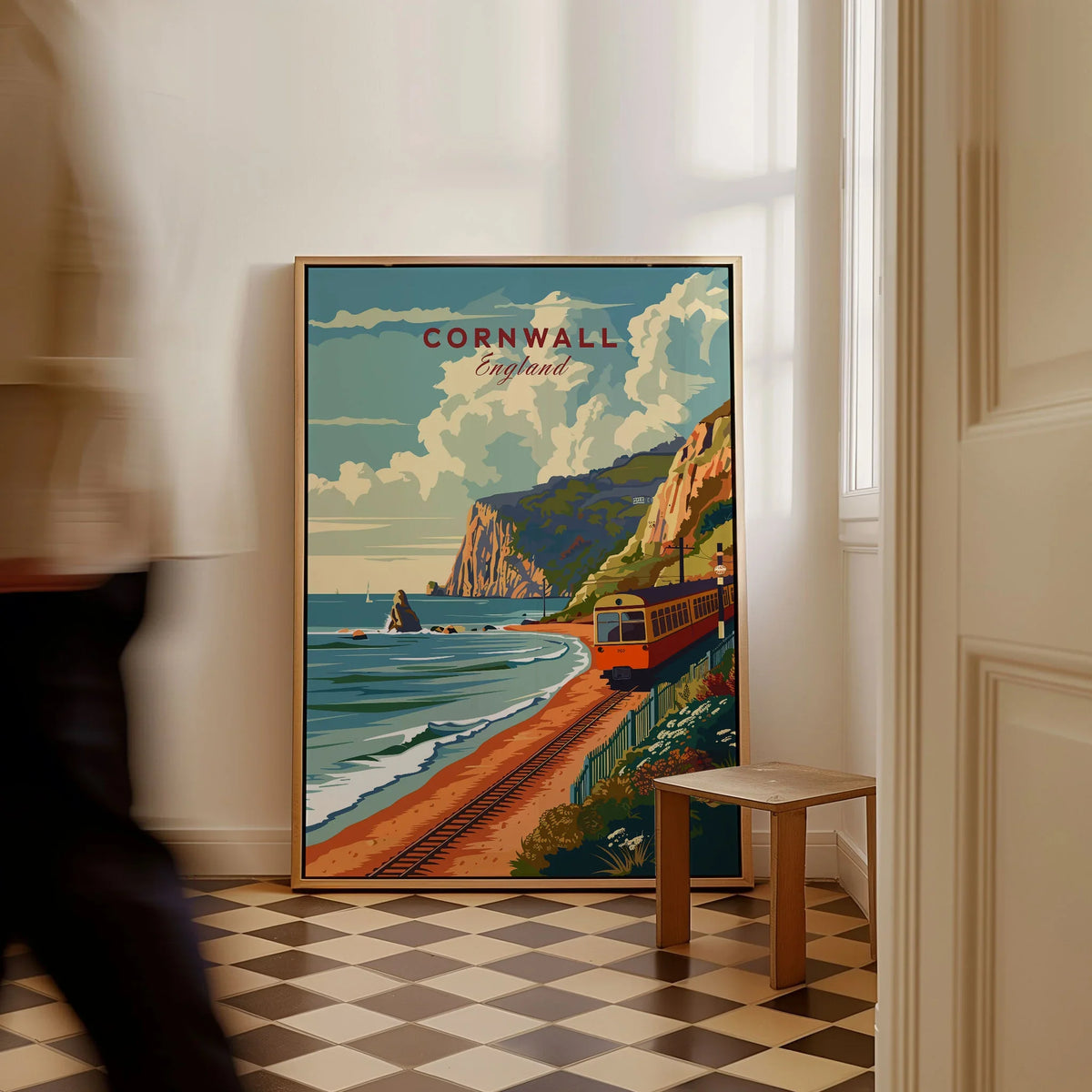 Cornwall Coast Travel Print as a framed canvas leaning in a hallway with a chequered tiled floor