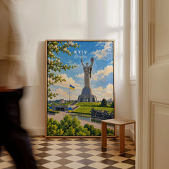 Kyiv Ukraine Motherland Monument Travel Poster — the Motherland Monument under spring blossom with the Ukrainian flag flying, shown as framed canvas on floor man walking past