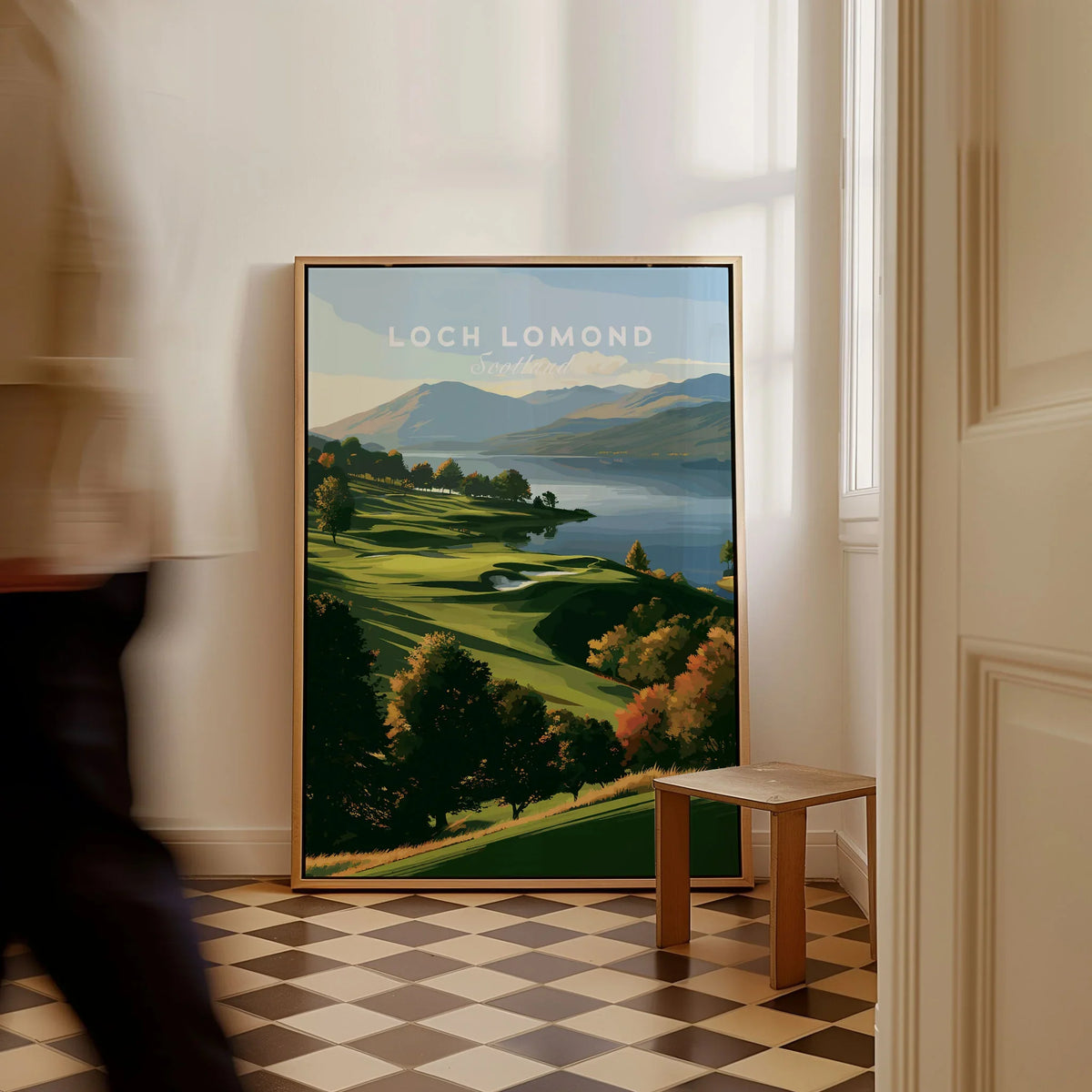 Loch Lomond Scotland Autumn Lochside Travel Poster — autumn slopes rolling down to Loch Lomond with Highland hills beyond, shown as framed canvas on floor man walking past