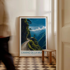 Camino de la Muerte Bolivia Cliff Road Wall Art — the Yungas cliff road curving along a jungle mountainside above the Bolivian Andes, shown as framed canvas on floor man walking past