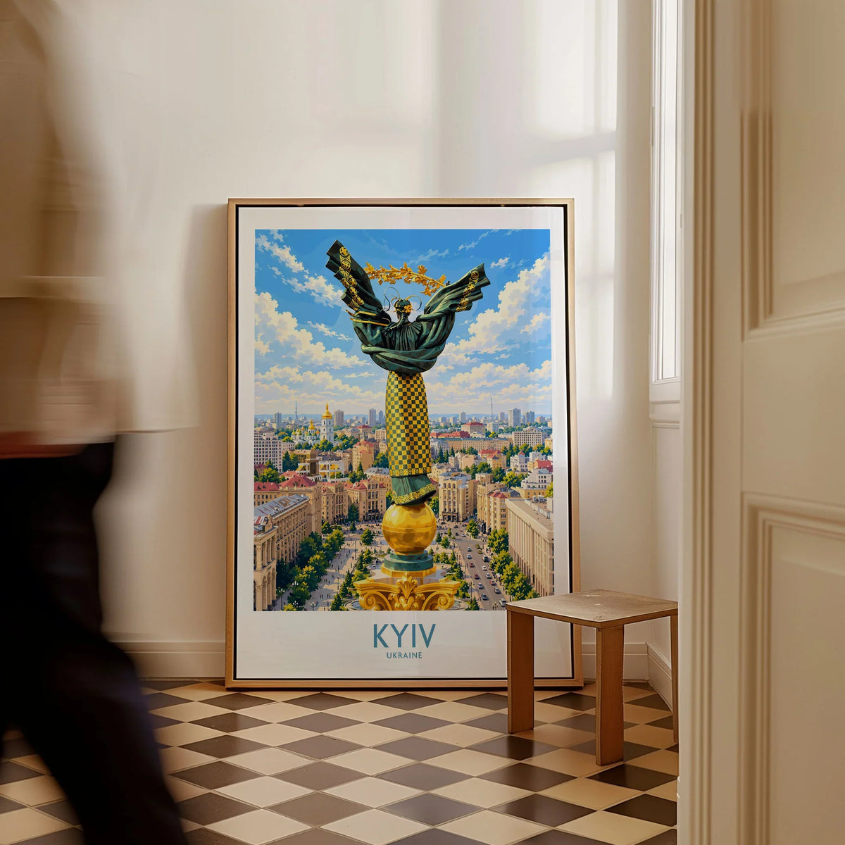 Kyiv Ukraine Maidan Square Wall Art — the Independence Monument rising above Maidan Nezalezhnosti and the Kyiv skyline, shown as framed canvas on floor man walking past