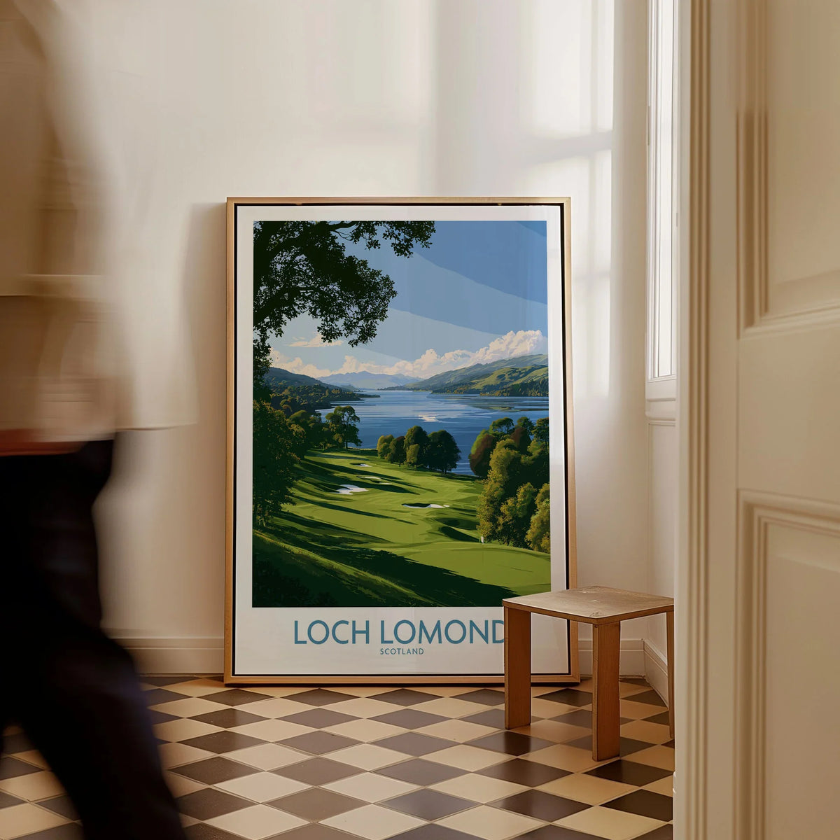 Loch Lomond Scotland Lochside Meadow Wall Art — a sunlit grassy shoreline running down to Loch Lomond under old oaks, shown as framed canvas on floor man walking past