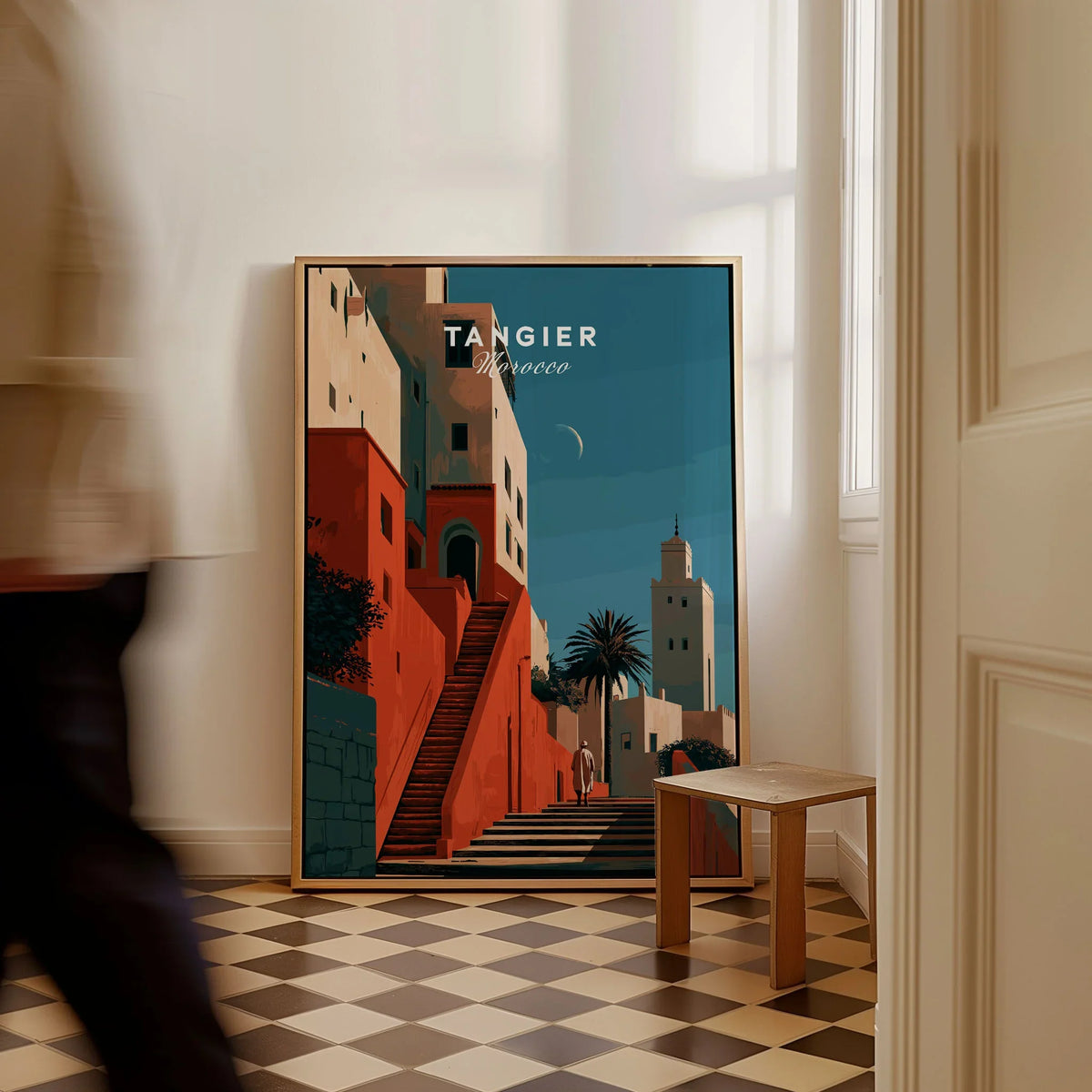 Tangier Morocco Kasbah Steps Travel Poster — coral kasbah steps climbing towards a minaret under a crescent moon, shown as framed canvas on floor man walking past