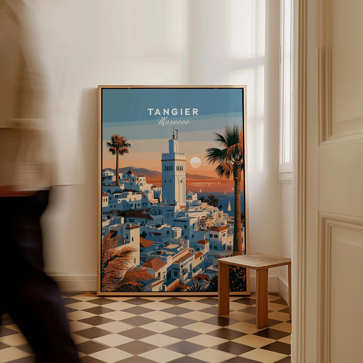 Tangier Morocco Sunset Medina Travel Poster — Tangier medina rooftops and a minaret above a bay dotted with sails, shown as framed canvas on floor man walking past