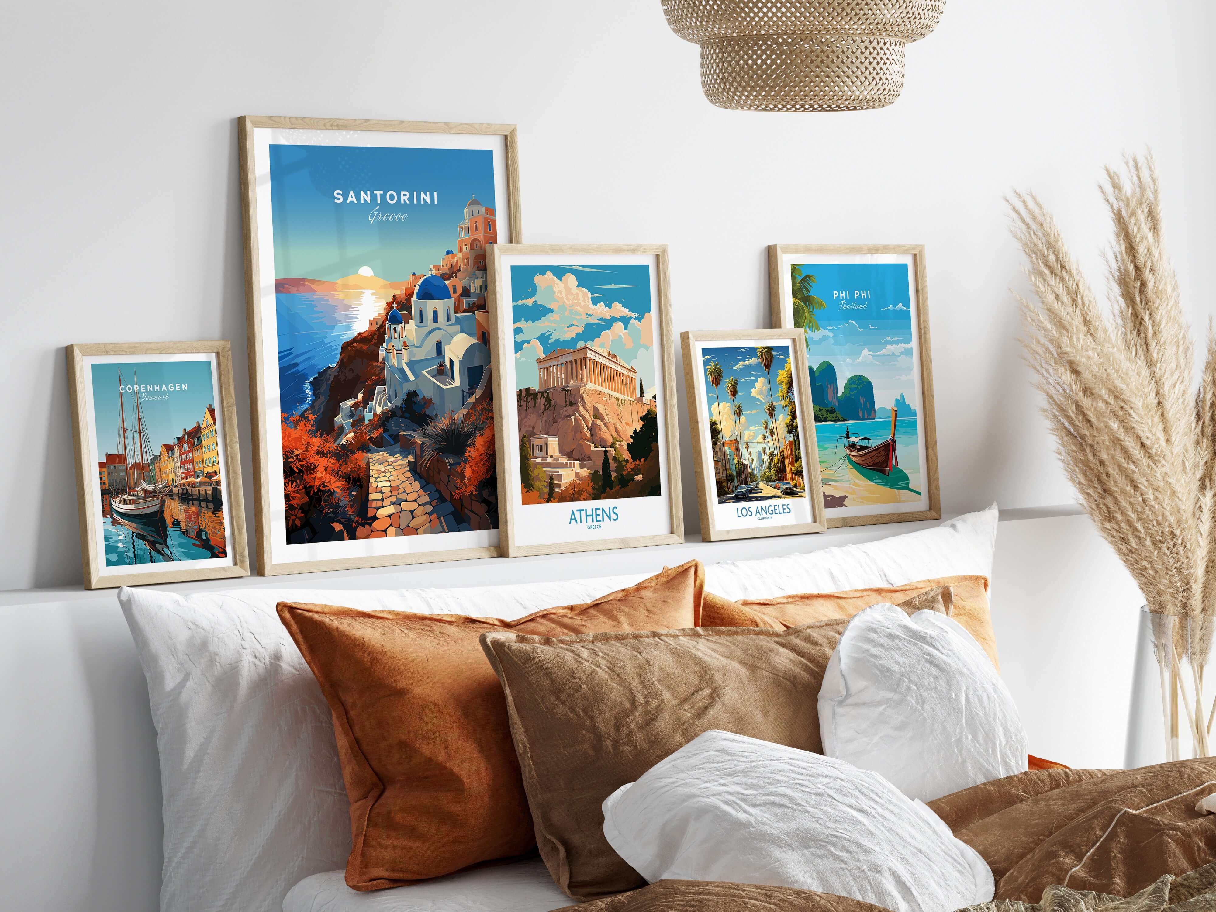 Set of five travel posters in natural frames all on a ledge above a bed. Travel poster destinations are Copenhagen, Santorini, Athens, Los Angeles and Phi-Phi island in Thailand. 