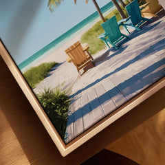 Close-up of a framed canvas art print showing colorful beach chairs, boardwalk, and ocean view.
