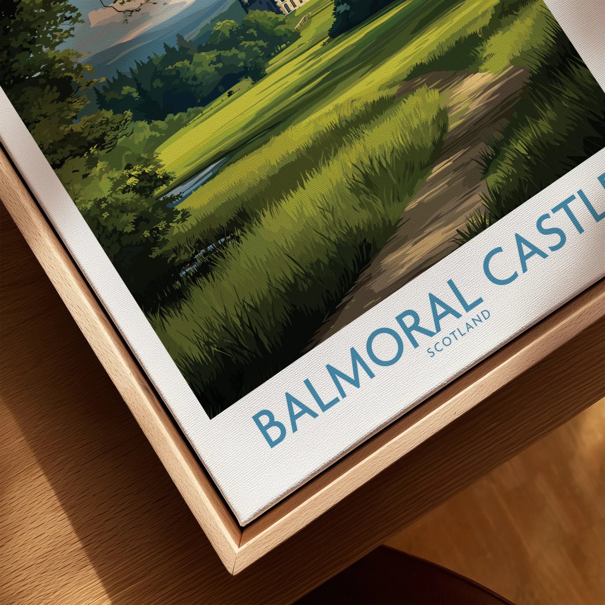 Close-up of Balmoral Castle travel poster in natural wood floating frame, canvas texture visible.