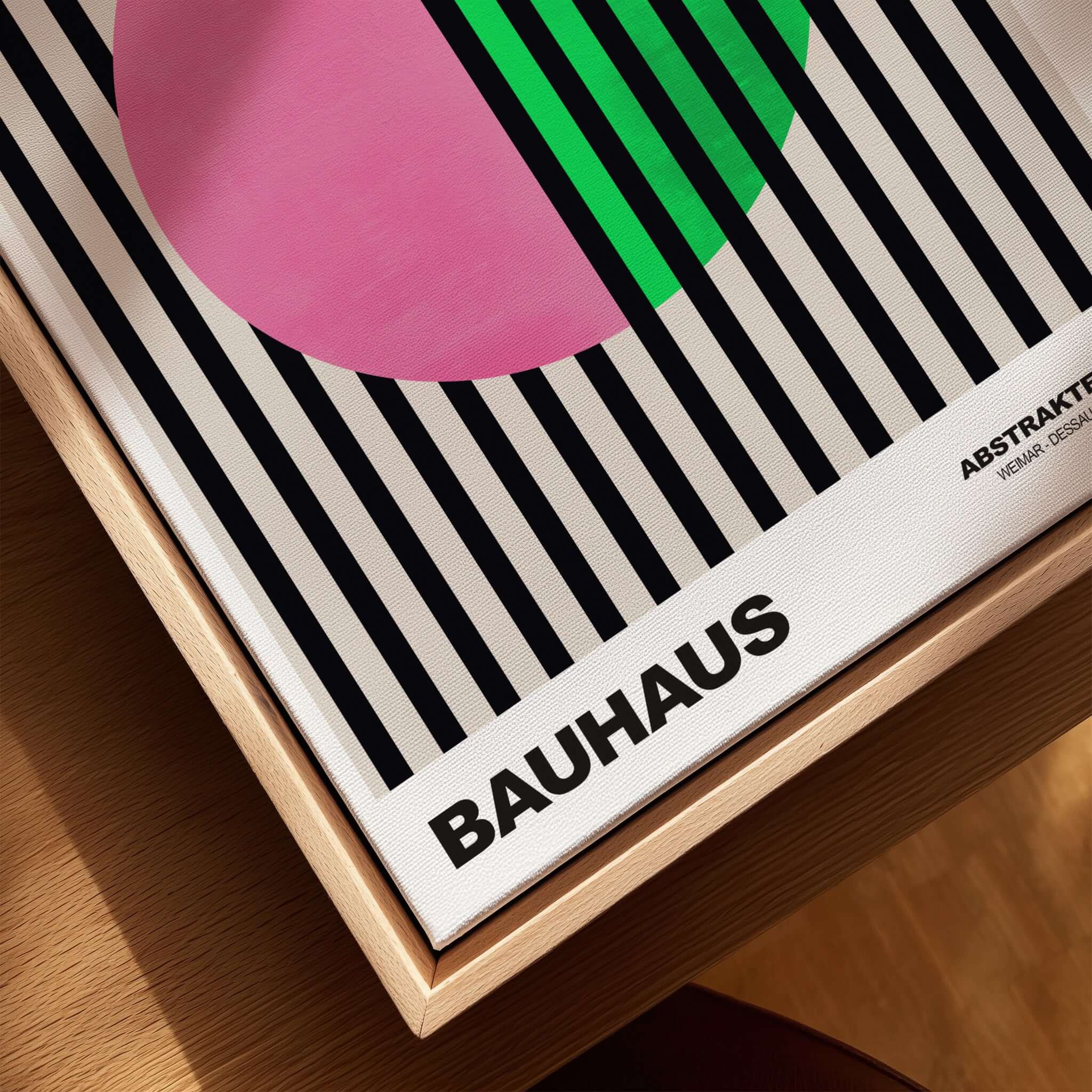 Bauhaus Exhibition Prints - Split Circle Abstract Art Print Pink Green Stripes displayed on a wooden surface.