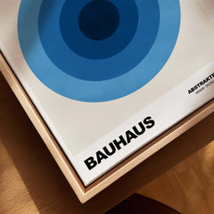 Bauhaus Exhibition Prints - Abstract Blue Circles Poster Geometric Design displayed in a frame with blue concentric circles.