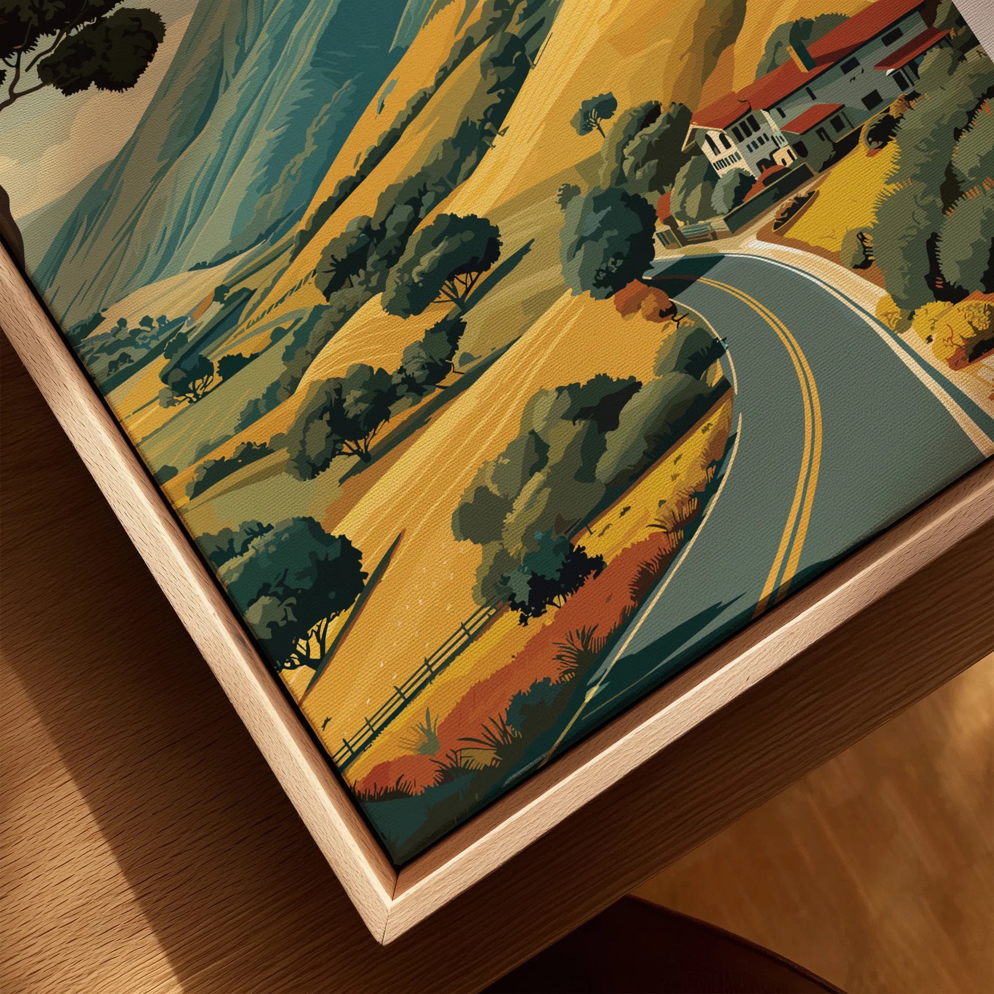 Closeup of a framed canvas print with a scenic road, hills, trees, and houses in natural colors