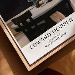 Edward Hopper Automat 1927 Des Moines Art Center Poster Print displayed on a wooden table with a cup of coffee.