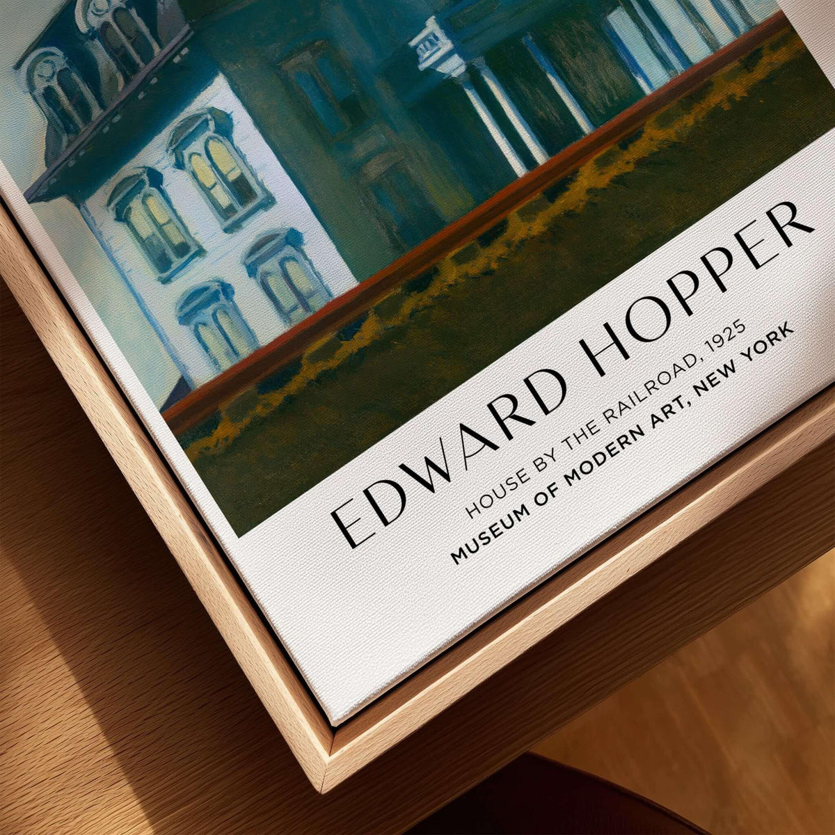 Edward Hopper House by the Railroad 1925 MoMA Art Print Poster displayed on a wooden surface.
