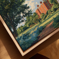 Closeup of canvas wall art with natural wood floating frame, featuring a red brick building, trees, and greenery in a landscape illustration.