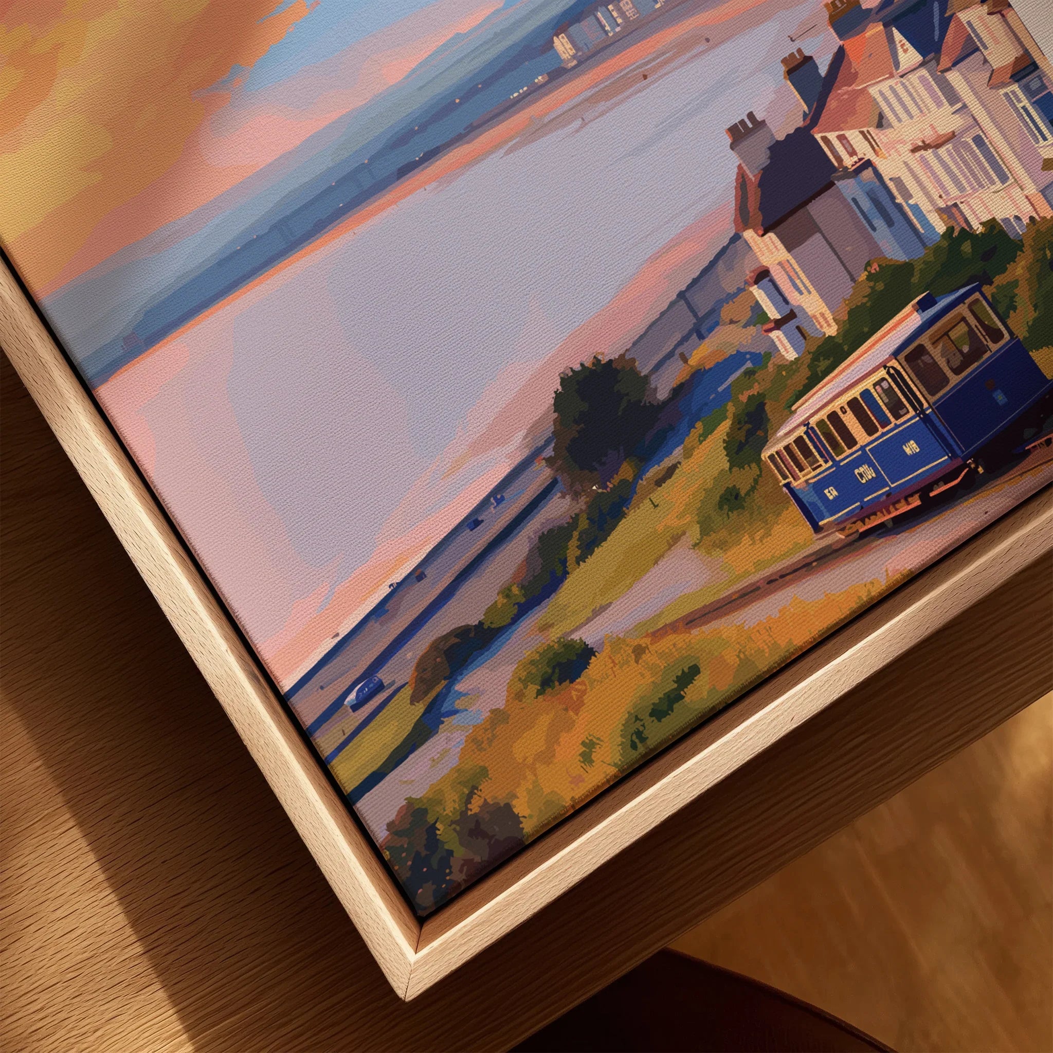 Closeup of framed canvas wall art featuring a vintage tram, coastal houses, and sunset view