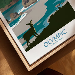 Closeup of Olympic National Park travel poster on canvas in natural wood floating frame, featuring a deer illustration by a coastal landscape.