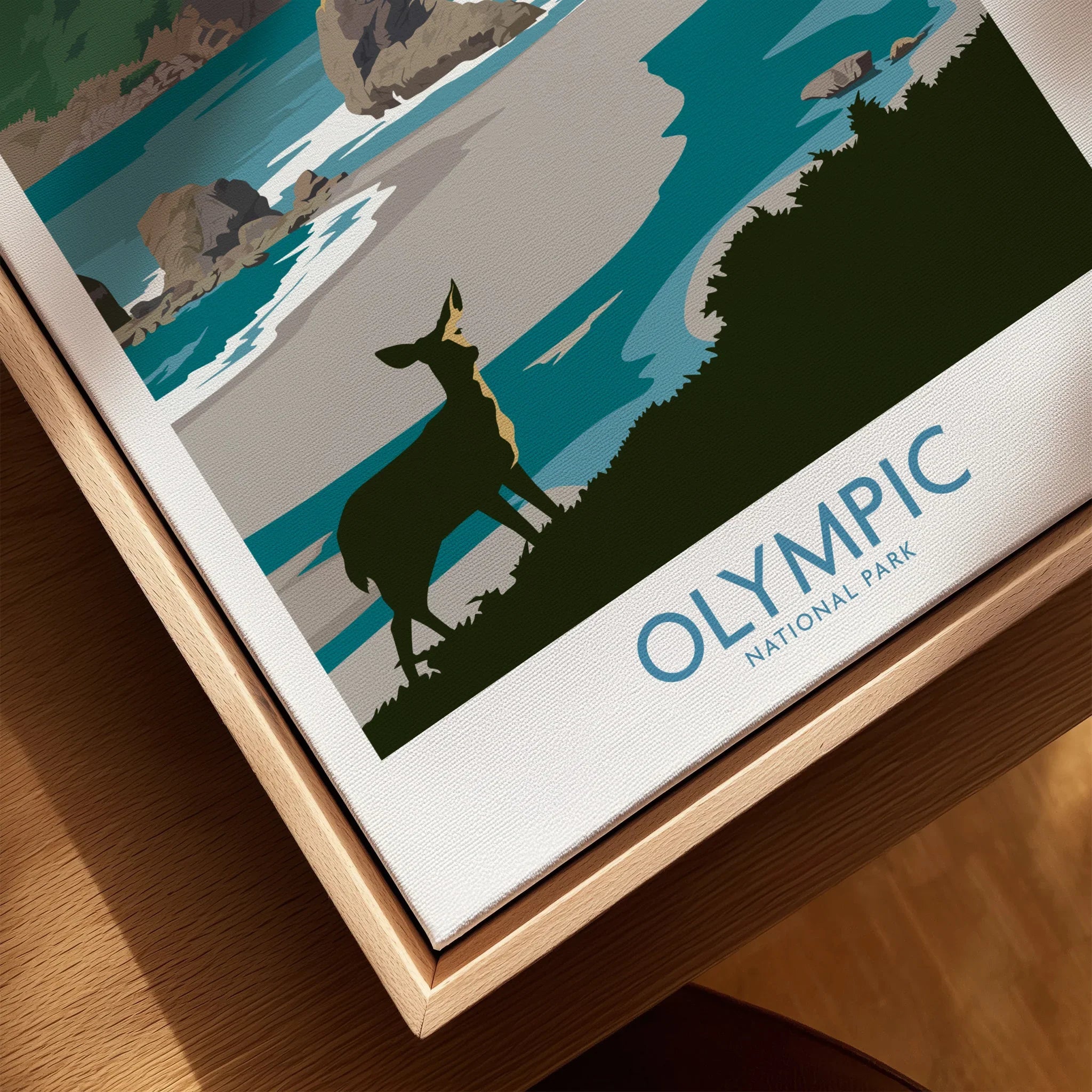 Closeup of Olympic National Park travel poster on canvas in natural wood floating frame, featuring a deer illustration by a coastal landscape.