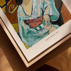 Matisse Poster - Algerian Woman 1909 Fauvist Wall Art Print displayed on a wooden table.