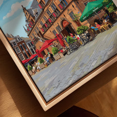 Closeup of cityscape canvas print in natural wood floating frame, featuring outdoor café scene.