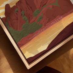 Closeup of framed canvas print featuring red rock cliffs, greenery, and a sunset landscape.