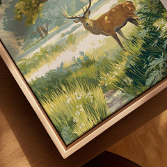 Close-up of framed canvas art featuring a stag in a scenic park landscape with green foliage.